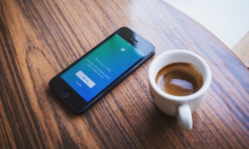 Photo of a cup of coffee and a smartphone with the twitter app open