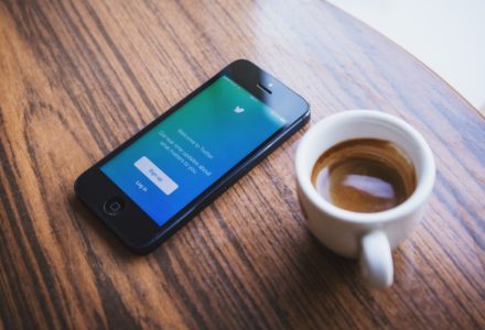 Photo of a cup of coffee and a smartphone with the twitter app open