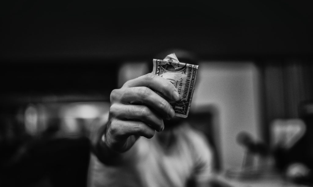 Black and white photo of a nurse practitioner holding up a one dollar bill
