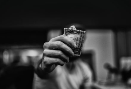 Black and white photo of a nurse practitioner holding up a one dollar bill